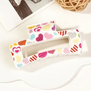 Detail of a large rectangular hair claw clip with colorful heart patterns on cream resin