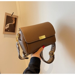 Détail d'un sac bandoulière en cuir grainé marron avec large sangle à motifs