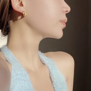 Close-up of elegant gold twisted hoop earrings worn by a model in soft lighting