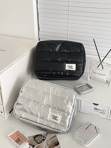 Detailed view of quilted puffer cosmetic bags in matte black and metallic silver finishes