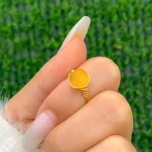 Detail of handmade gold wire-wrapped ring featuring a bright yellow round gemstone