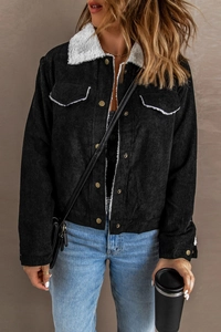 Detail of black corduroy jacket with white sherpa collar and metal button closure
