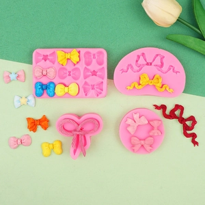 Detailsicht auf rosa Silikon-Schleifenformen mit bunten Fondantproben auf Pastellhintergrund