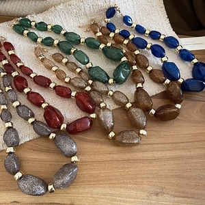 Macro view of colorful glitter acrylic beaded necklaces with gold metal spacers