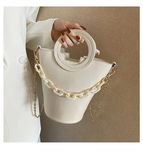 Detailed view of cream leather handbag with circular handle and decorative acrylic chain