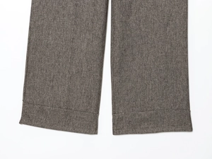 Detailed close-up of dark grey herringbone pants cuffs showing fine fabric texture