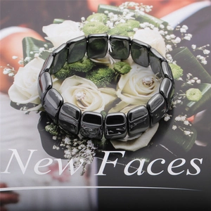 Detailed view of polished black hematite square beads on a stylish floral background