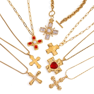 Collezione di collane con croce in oro e acciaio con pietre rosse e perle su bianco