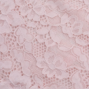 Close-up of pink floral lace fabric showing delicate hollow patterns and woven texture