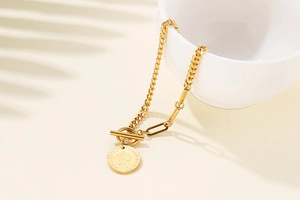 Detail of gold chain bracelet with toggle clasp and Elizabeth II coin pendant