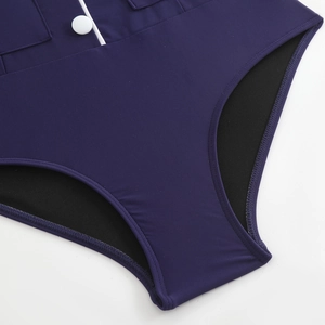 Detail of navy blue one-piece swimsuit with white trim and a decorative round button