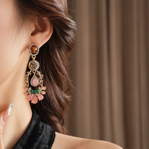 Dettagli di orecchini vintage stile palazzo con gemme a goccia e cristalli sulla modella