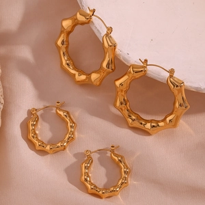 Detail of bamboo-style 18K gold plated U-shaped acrylic earrings on pink silk