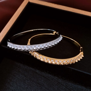 Macro shot of gold and silver spike bangles with crystals on black velvet display