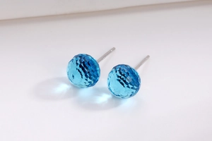 Macro shot of S925 silver stud earrings featuring light blue faceted crystal balls