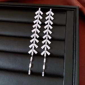 Detail view of silver tassel earrings with zircon leaf design on black leather background