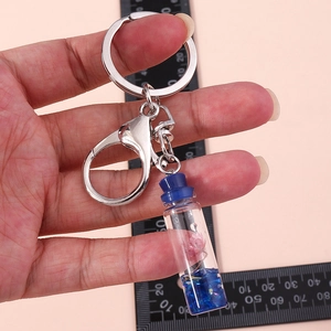Detail of wish bottle keychain with pink flower and blue crystals next to a ruler