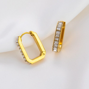 Macro shot of 18K gold plated rectangular earrings with clear zircon stones on silk