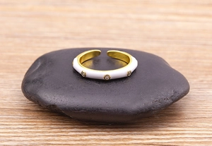 Detail view of 18K gold plated ring with white enamel and sparkling zircon accents