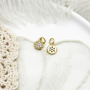 Macro view of gold sun pendants with clear stones on a soft white feather background