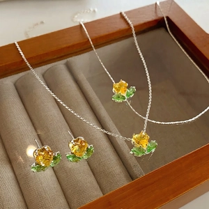 Luxury silver jewelry set with yellow heart zircons and green leaf accents on tray