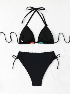 Close-up of black triangle bikini top featuring colorful embroidery and neck tie straps