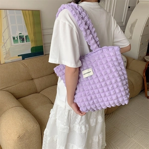 Detail of light purple popcorn texture tote bag with brand label and wide shoulder strap