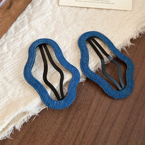 Detailed macro view of denim fabric wrapped irregular wavy hair clips on a wooden surface