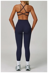 Detail of navy blue high-waist yoga pants and cross-back sports bra on female model