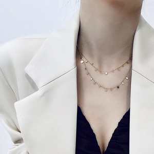 Detail of layered gold titanium necklace featuring square and teardrop pendants on a model