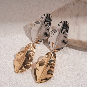 Irregular metal leaf stud earrings in gold and silver finish shown on a marble block