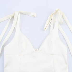 Détail d'un top en satin blanc avec décolleté en V profond et bretelles à nœuds élégantes
