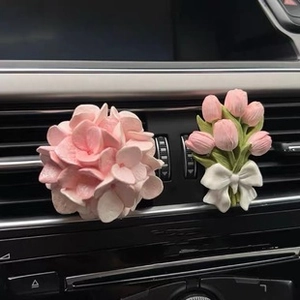 Detailed view of pink hydrangea and tulip car air vent clips on dashboard