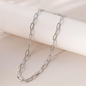 Close-up of silver paperclip link chain necklace with textured finish on a white stand