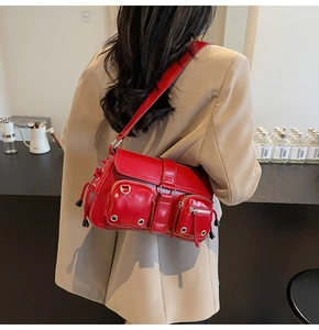 Detail of red glossy leather shoulder bag with silver zippers and utility pockets