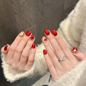 Unghie finte natalizie fatte a mano con glitter rossi e oro e decorazioni a fiocco 3D