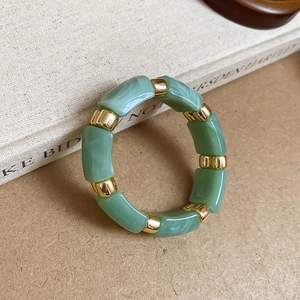 Detail shot of green marble acrylic rectangular beads with gold metal spacers on elastic cord