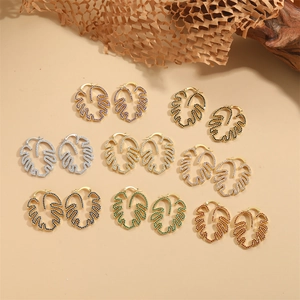 Elegant monstera leaf earrings with colorful cubic zirconia pavé on minimalist wood base