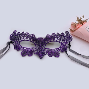 Detailed flat lay of a purple lace masquerade mask with black ribbons and dried roses