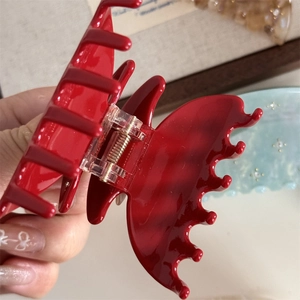 Close-up of red acetic acid butterfly hair claw with rhinestones and glossy finish