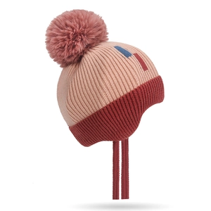 Pink and red knit winter hat for babies with large pom pom and earflaps on white background