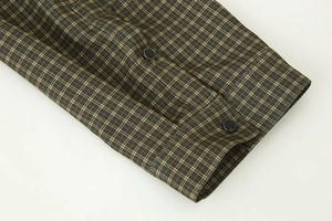 Detail shot of plaid shirt cuffs in olive green and yellow with black buttons
