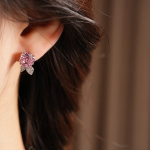 Dettaglio orecchino a fiore rosa e foglia con zirconi e finitura in argento