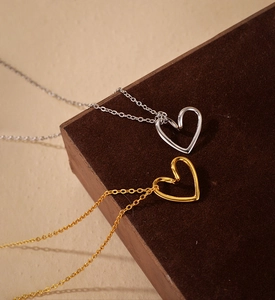 Close-up of elegant gold and silver hollow heart necklaces on dark wood surface
