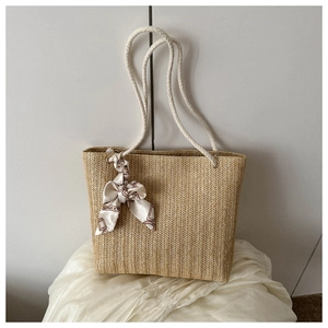 Détail du sac cabas en paille avec anses en coton blanc et foulard en soie décoratif