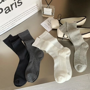 Detailed macro view of four ribbed calf socks in black, grey, and beige cotton blend