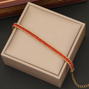 Detail of adjustable gold tennis bracelet featuring rows of vibrant red crystals