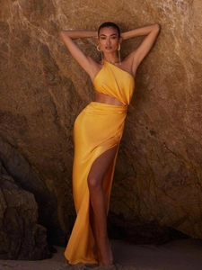 Detail of yellow satin one-shoulder dress with side slit and waist cutout on a rock cliff