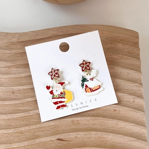 Detail of Christmas earrings featuring Santa Claus and winter house with snowflake studs