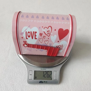 Pink heart tinplate mailbox gift box shown being weighed at 126.2g for shipping